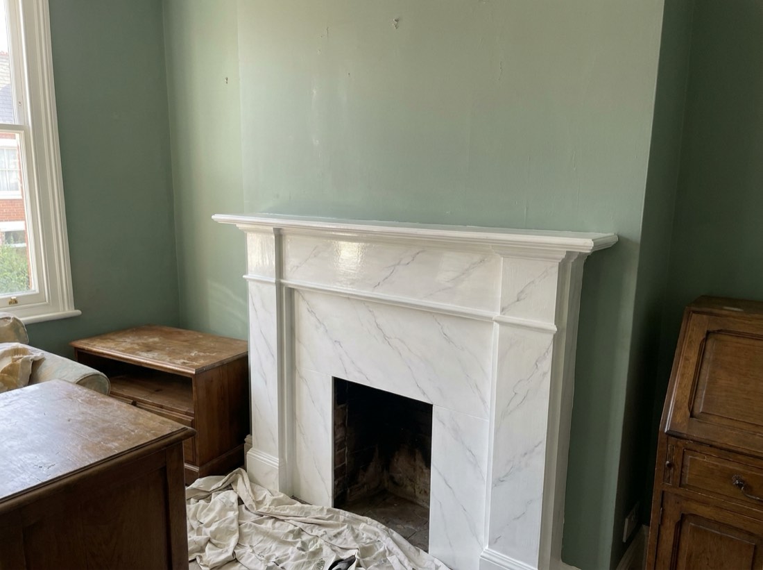 Painted fire surround with a white faux marble finish and soft grey veining