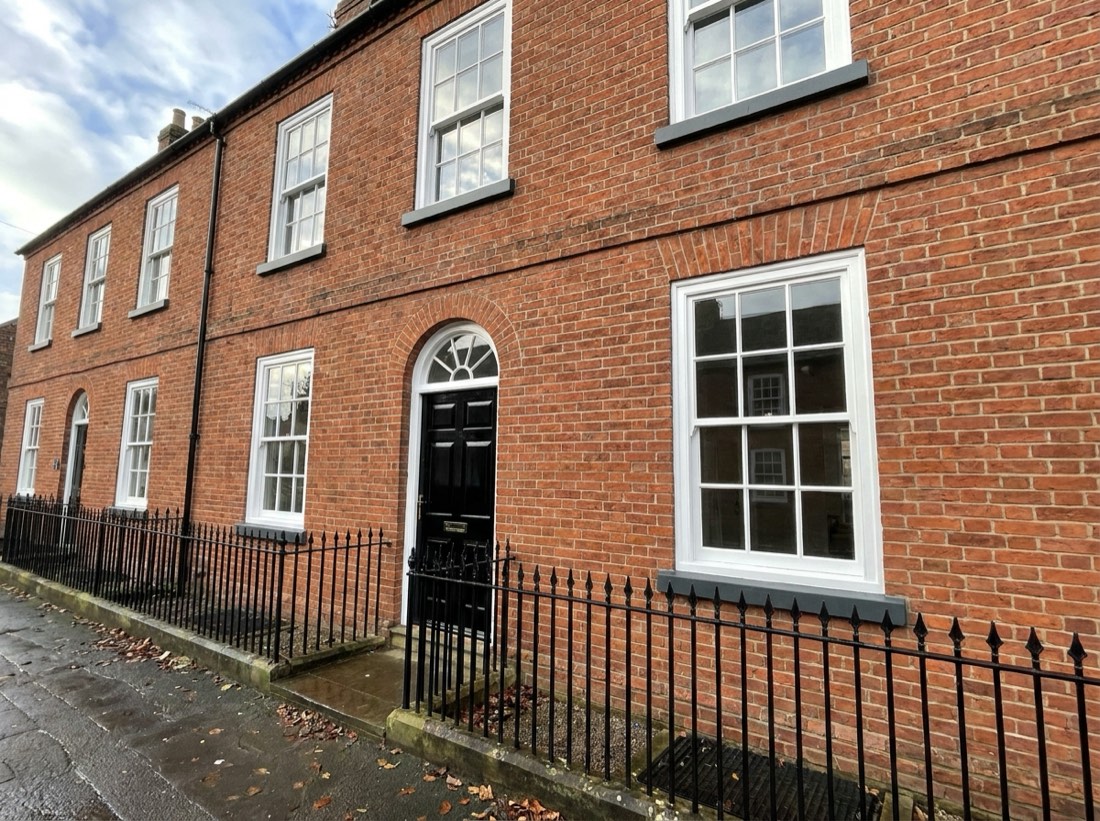 Georgian brick townhouse with freshly painted white sash windows, black front door and railings