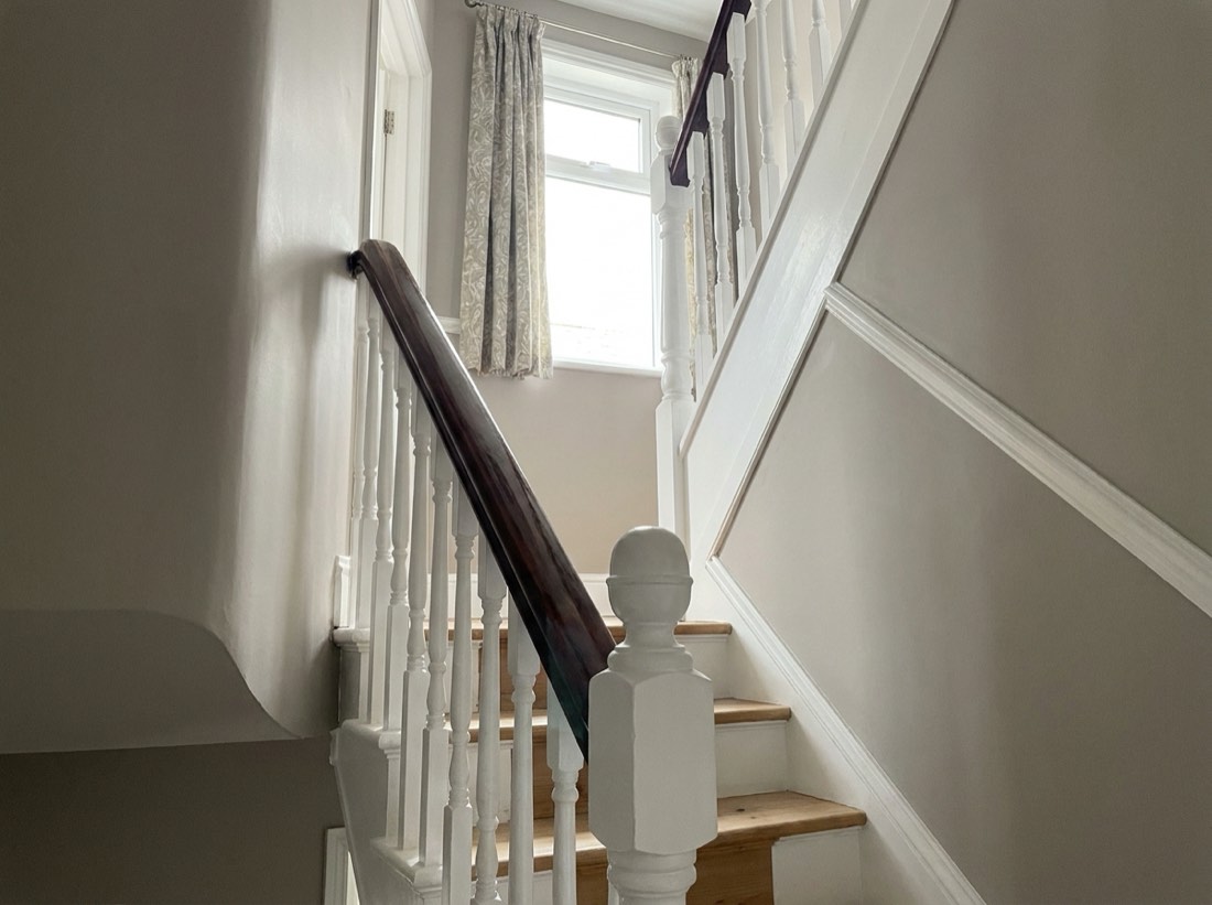 Freshly painted staircase with white spindles, newel post and strings and a dark handrail